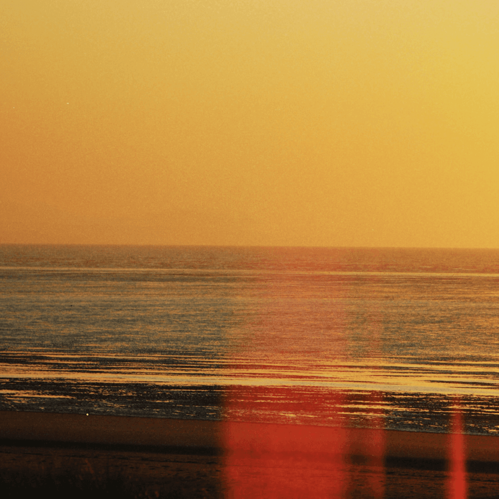 The scene is set outdoors at a tranquil beach, captured during the serene moments of sunset.