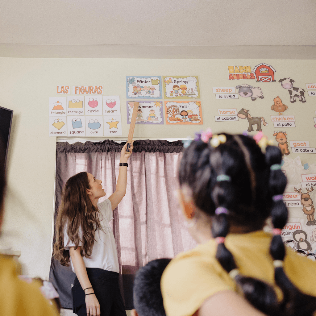 The scene unfolds indoors within a lively classroom setting during the daytime, as indicated by the bright interior lighting.