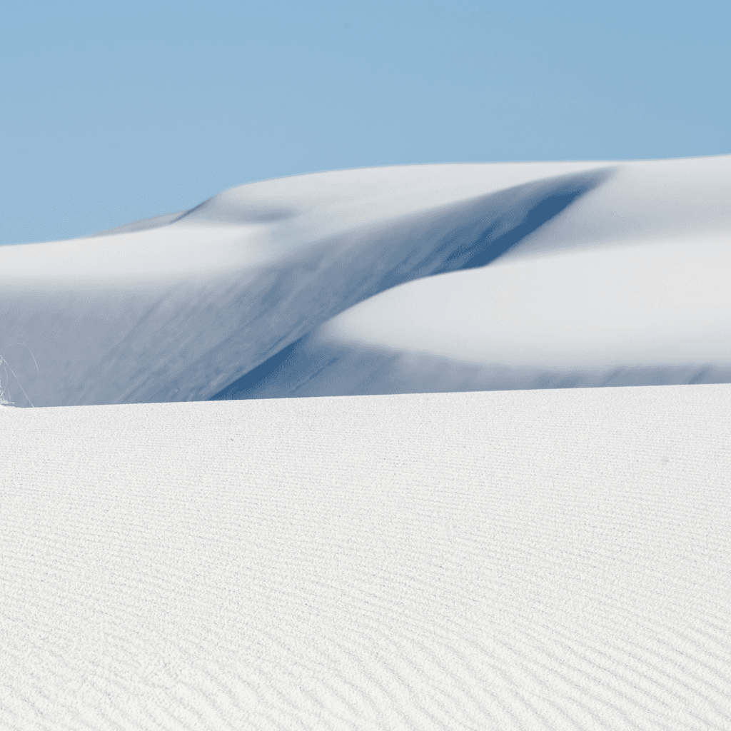 The scene takes place outdoors in a vast desert landscape, characterized by smooth, undulating dunes of white sand that stretch into the distance.