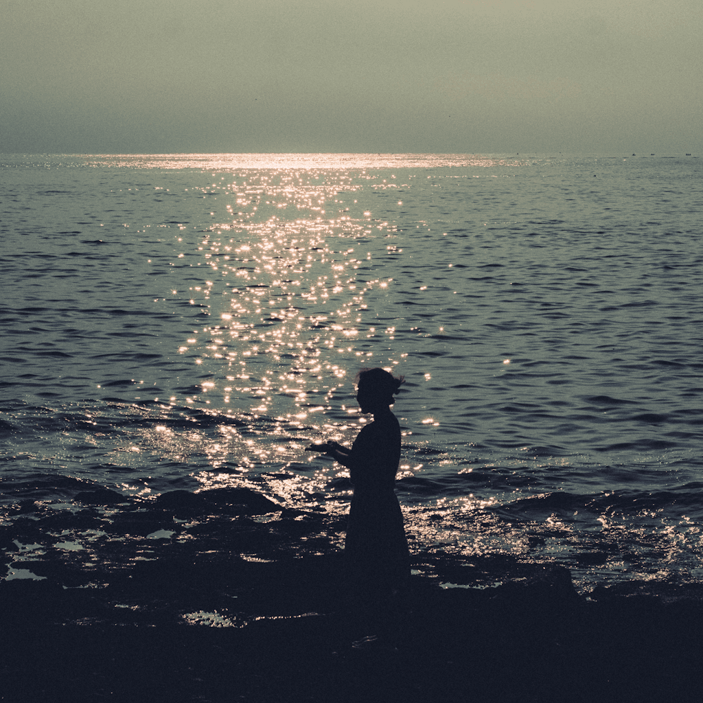 The scene is set outdoors by a tranquil seaside during the soft glow of early evening.