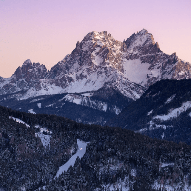 The scene is set outdoors in a breathtaking mountainous landscape, captured during the gentle fade of dusk.