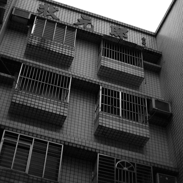 The scene is outdoors, featuring a multi-story building with a tiled facade.