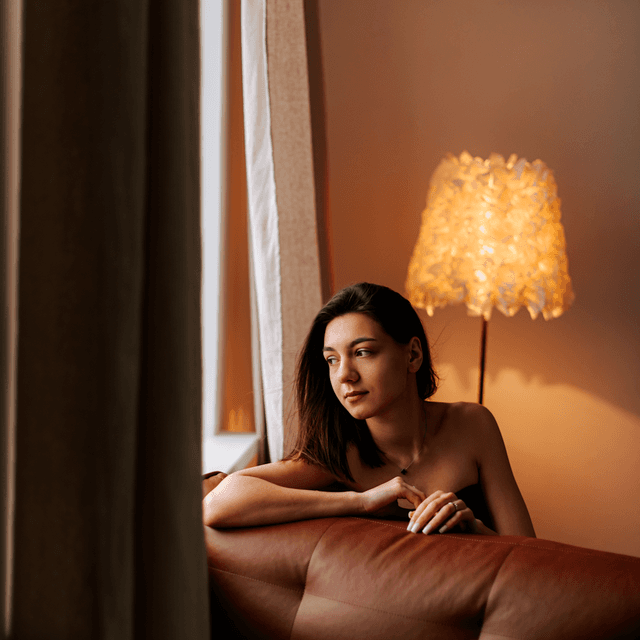 The scene is set indoors, characterized by the warm and cozy ambiance created by the soft, ambient glow of a stylish floor lamp with a decorative shade.