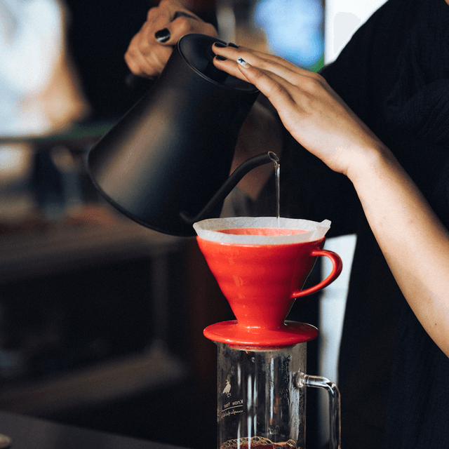 The scene is set indoors, likely in a cozy kitchen or a coffee shop, with soft lighting that suggests either early morning or late afternoon.