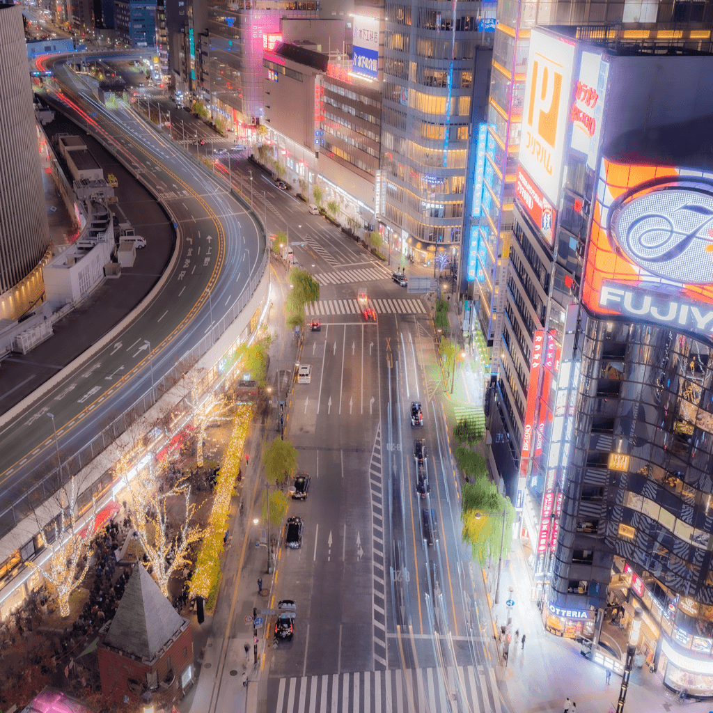 The scene is an urban nighttime setting, likely a bustling city center.